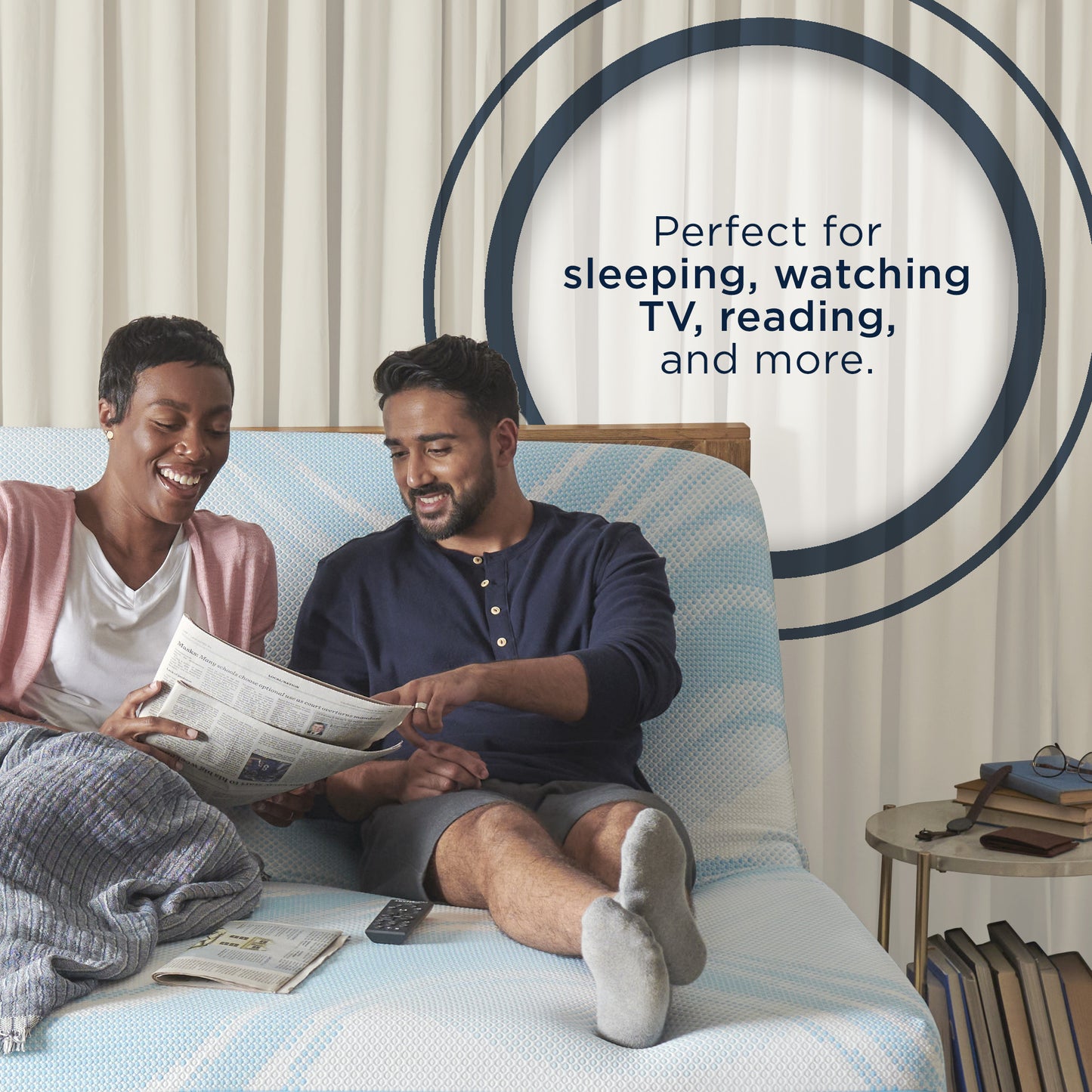 Smiling couple reading and relaxing on a TEMPUR-Ergo adjustable base with head elevated, highlighting comfort for watching TV, sleeping, and reading