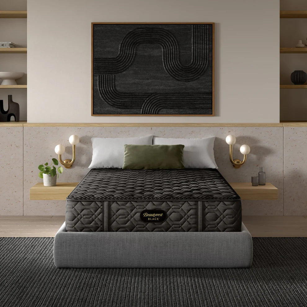 Gray mattress on a bed in a modern bedroom with abstract art and shelves.