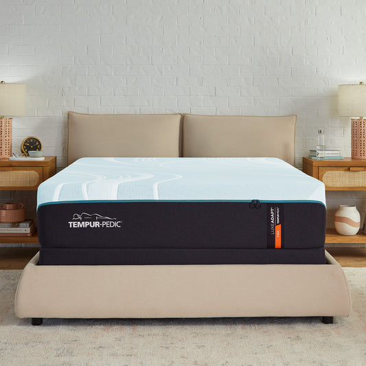 Tempur-Pedic LuxeAdapt® Firm mattress in a cozy modern bedroom with beige upholstered bed and wooden nightstands, showcasing its elegant design and firm support.