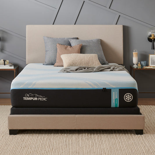 Tempur-Pedic ProBreeze® Medium mattress in a modern bedroom setting with a light upholstered bed frame and cozy decorative pillows, showcasing its cool-to-the-touch cover and temperature-regulating design.