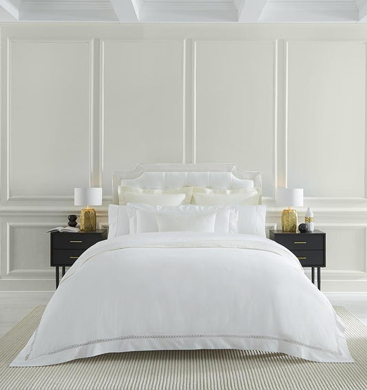 Roupa de cama SFERRA em uma cama arrumada em um quarto
