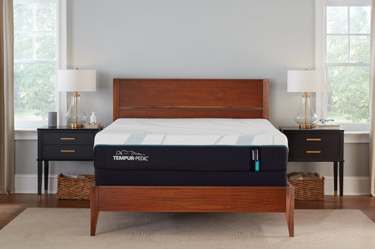 Tempur-Pedic Adapt Medium mattress displayed in a modern bedroom with wood furniture and natural light.